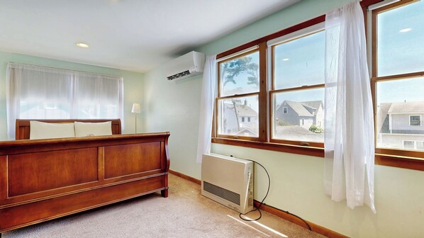 A bedroom with a wooden bed, a radiator, and large windows with curtains. - Hank's Hideaway by Bayley Vacation Rentals (Scarborough)