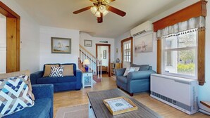 A living room with two sofas, a coffee table, and a ceiling fan. There is a staircase leading to another room, and a radiator on the wall. - Hank's Hideaway by Bayley Vacation Rentals (Scarborough)