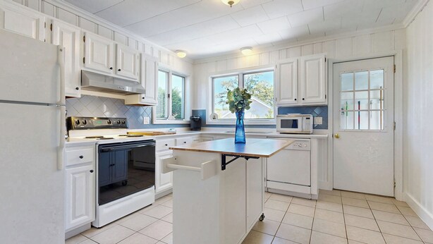 A kitchen with white cabinetry, a central island, a microwave, and a stove. - Hank's Hideaway by Bayley Vacation Rentals (Scarborough)