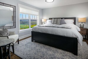 A bedroom with a large window, a bed with a headboard, two bedside tables with lamps, a chair, and a patterned rug. - 360 Degree Vineyard Views, Four Master Suites, Free Wine Tastings for Group, Ping Pong, Fire-Pit (Yamhill)