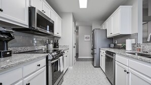 Une cuisine moderne avec des meubles blancs, des appareils en acier inoxydable et un carrelage décoratif.