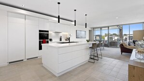 A modern kitchen with white cabinetry, a central island, and pendant lighting.