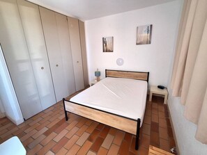 A bedroom with a bed, a wardrobe, a nightstand, and two wall-mounted paintings. - MAGNIFIQUE APPARTEMENT AVEC VUE IMPRENABLE SUR LA MER (LE CAP D AGDE)