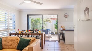 Cozinha moderna com área de refeições, um sofá e vista para o quintal.