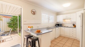 Cozinha moderna com armários brancos, micro-ondas embutido e uma ilha grande com banquetas.