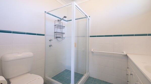 A bathroom with a glass-enclosed shower, white tiles, and a teal accent border. - 1/94 Rocky Point Rd - Duplex with Aircon, Foxtel and Short Walk To The Sports Club (Fingal Bay)