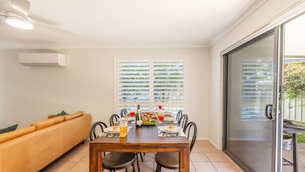 Uma área de refeições com uma mesa de madeira, cadeiras e um sofá.