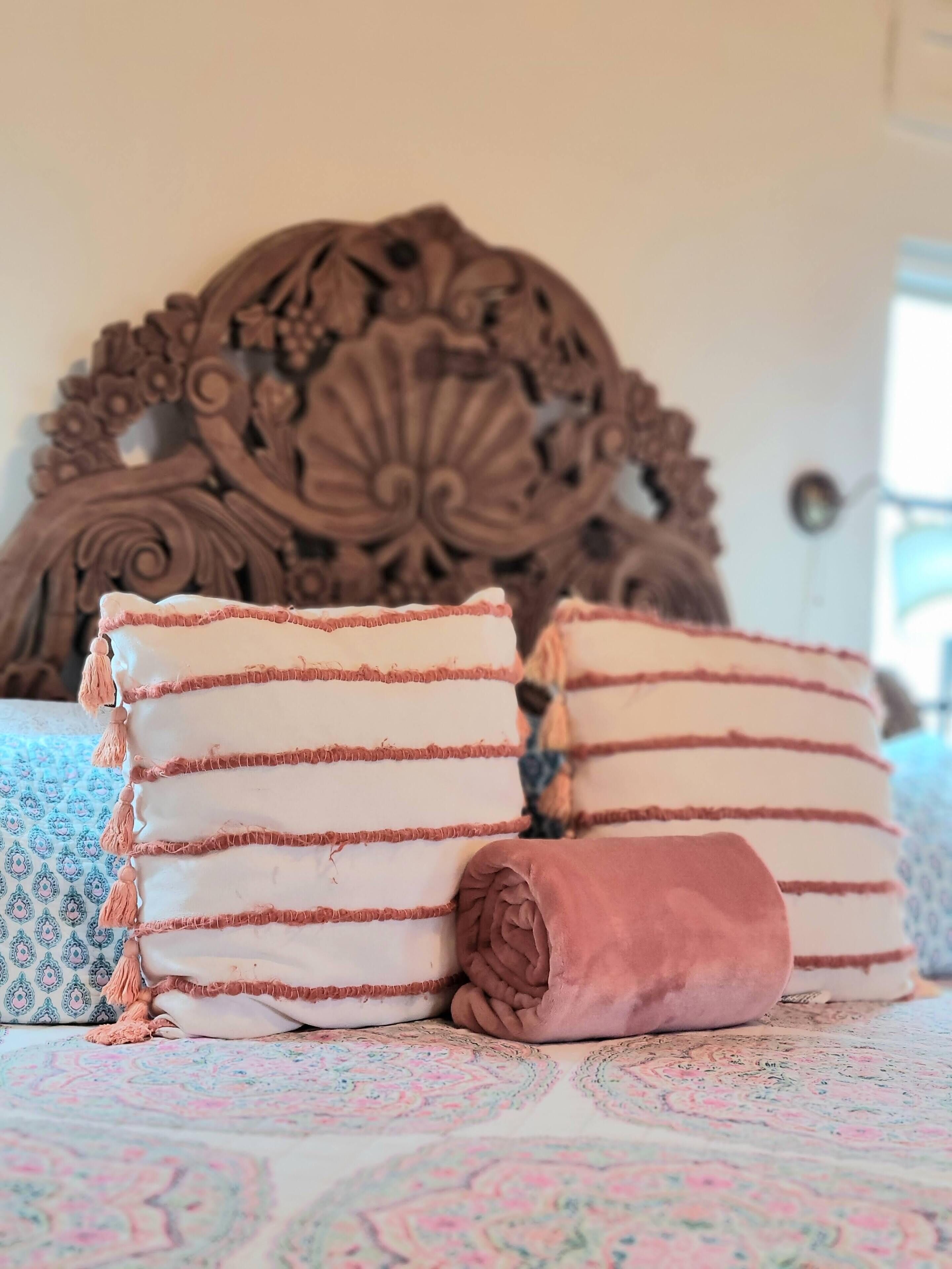 Una cama con cabecera decorativa y ropa de cama estampada.