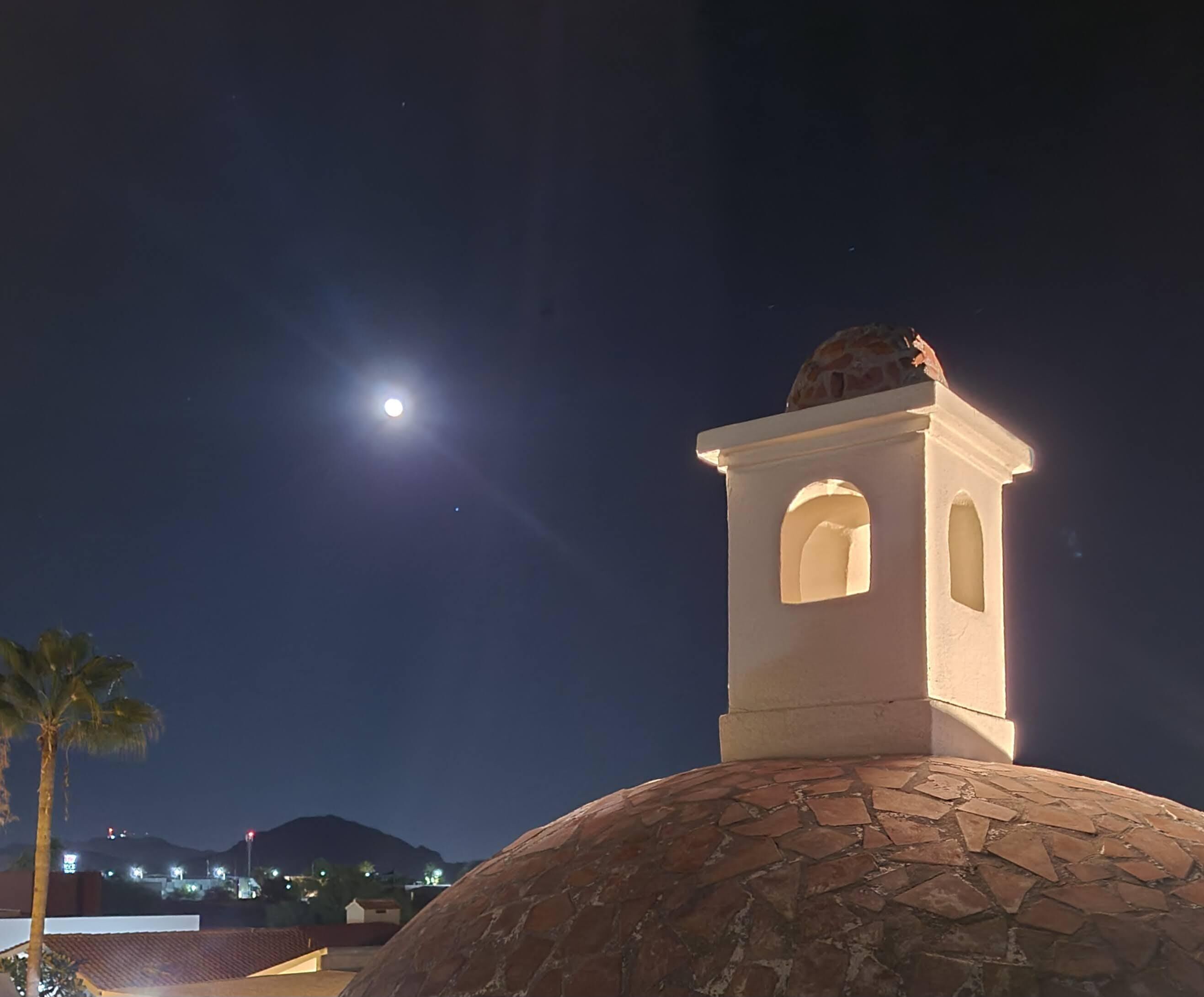 Una escena nocturna con una cúpula iluminada por la luna y una pequeña torre con ventanas de arco.