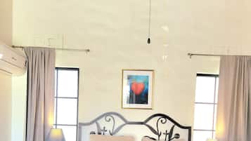 Una camera da letto con un letto, due comodini, una lampada a sospensione, un quadro appeso al muro e una finestra con tende.