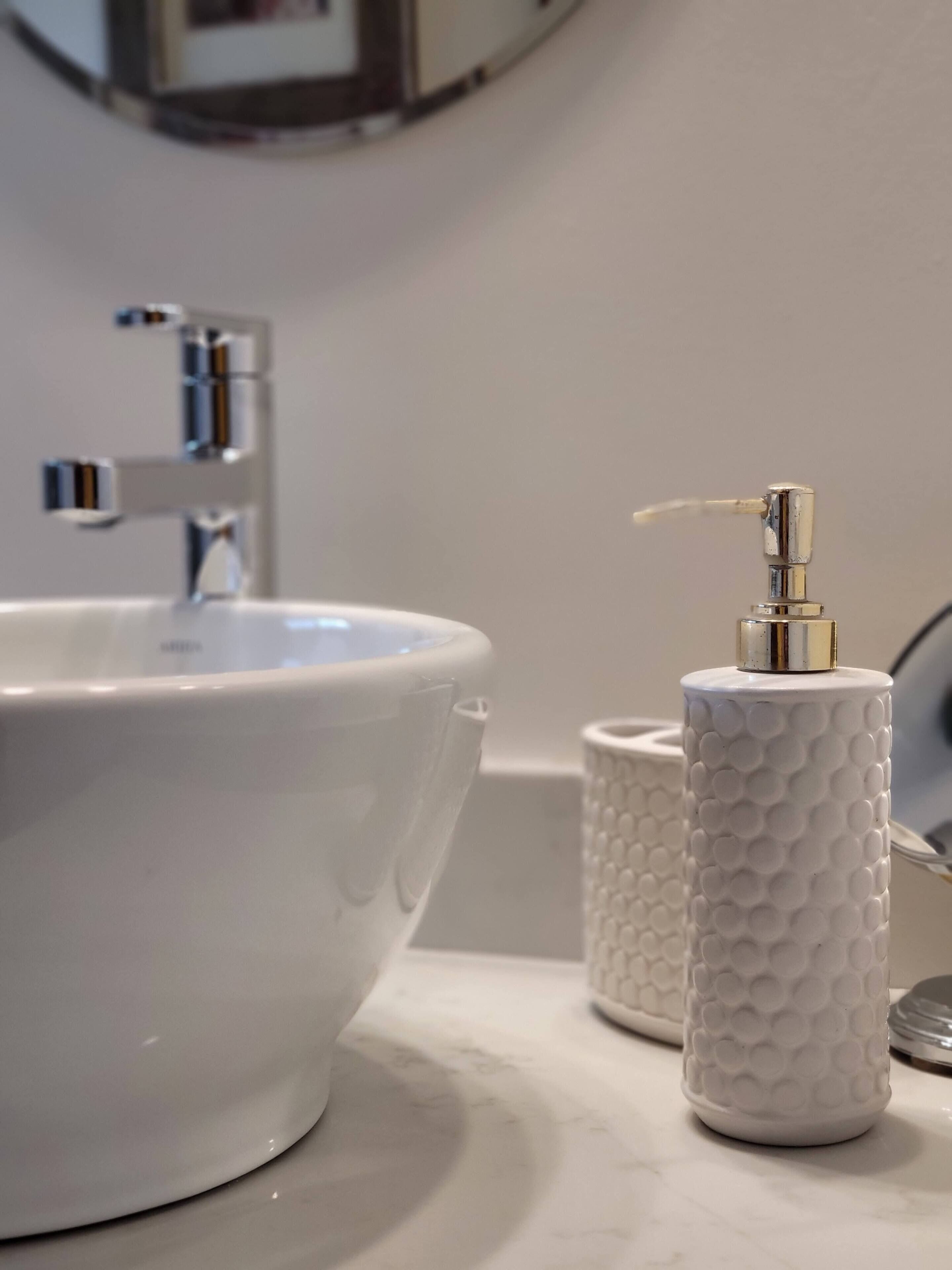 A bathroom sink with a modern faucet, a soap dispenser, and a textured soap holder.