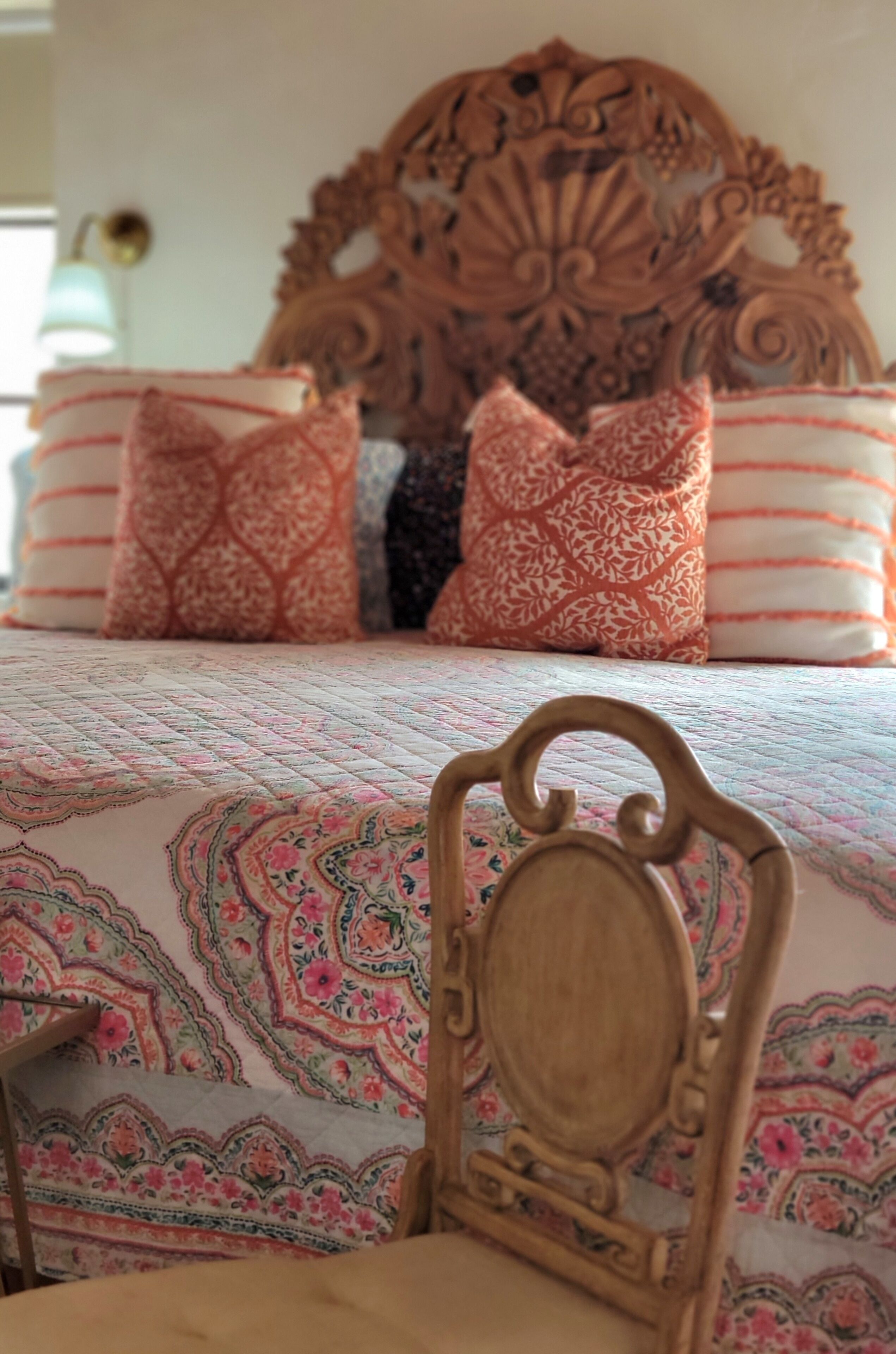A bed with a floral-patterned bedspread and a wooden headboard.
