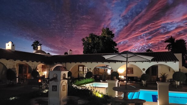 A courtyard with a swimming pool, outdoor seating, and a sunset sky. - Casa Magdalena B&B (San Carlos)