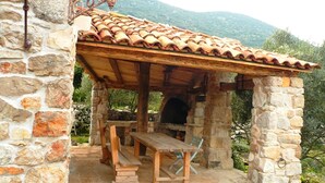Un edificio de piedra con techo de tejas, una banca de madera y una mesa.