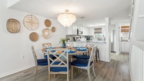 Une cuisine moderne avec des meubles blancs, un îlot central et un lustre.