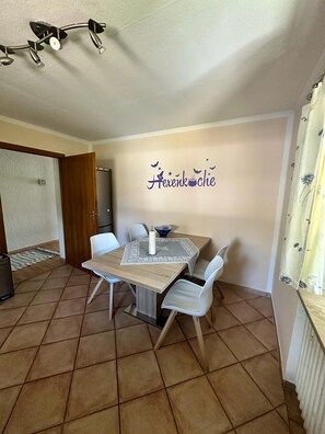 A dining area with a table, chairs, and a wall decoration.