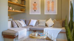 A cozy living room with a sectional sofa, wooden shelves, and two abstract paintings. - Lovely in the Heart of Town steps from everything (Tamarindo)