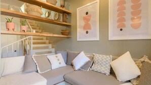 A modern living room with a sectional sofa, a staircase, and decorative wall art. - Lovely in the Heart of Town steps from everything (Tamarindo)