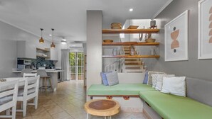 A modern living room with a green sofa, a wooden coffee table, and a staircase leading to an upper level. - Lovely in the Heart of Town steps from everything (Tamarindo)