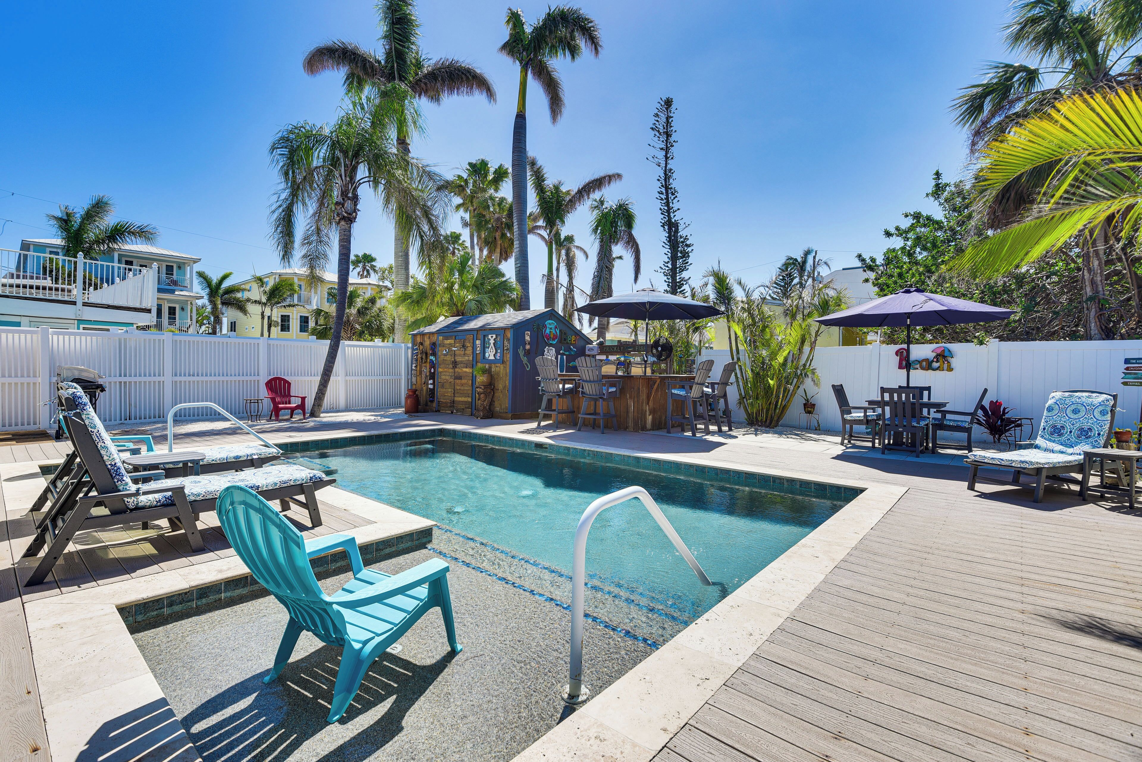 A pool area with lounge chairs, a bar, and a wooden deck.
