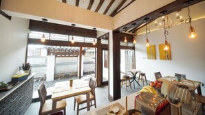 A dining area with wooden beams, hanging light fixtures, and a view of the outside. - Naganjae (Gyeongju)