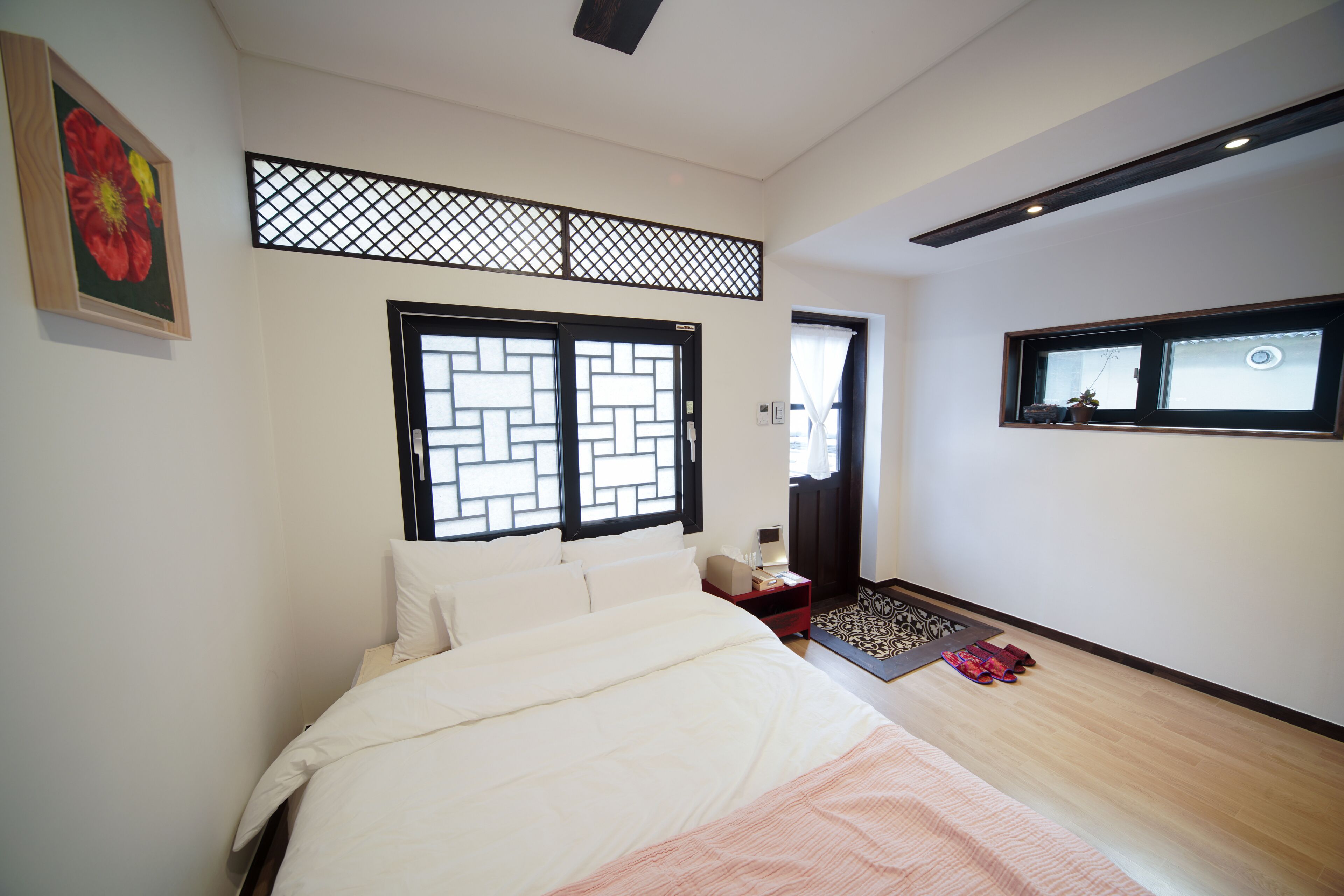A bedroom with a bed, a nightstand, a window with a view, and a decorative screen.