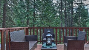 A wooden deck with wicker furniture and a lantern. - 4 Mi to Big Tree State Park: Serene Cabin w/ Deck (Arnold)