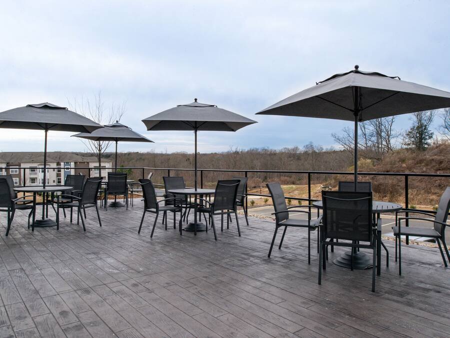 An outdoor patio area with tables and chairs, surrounded by umbrellas.