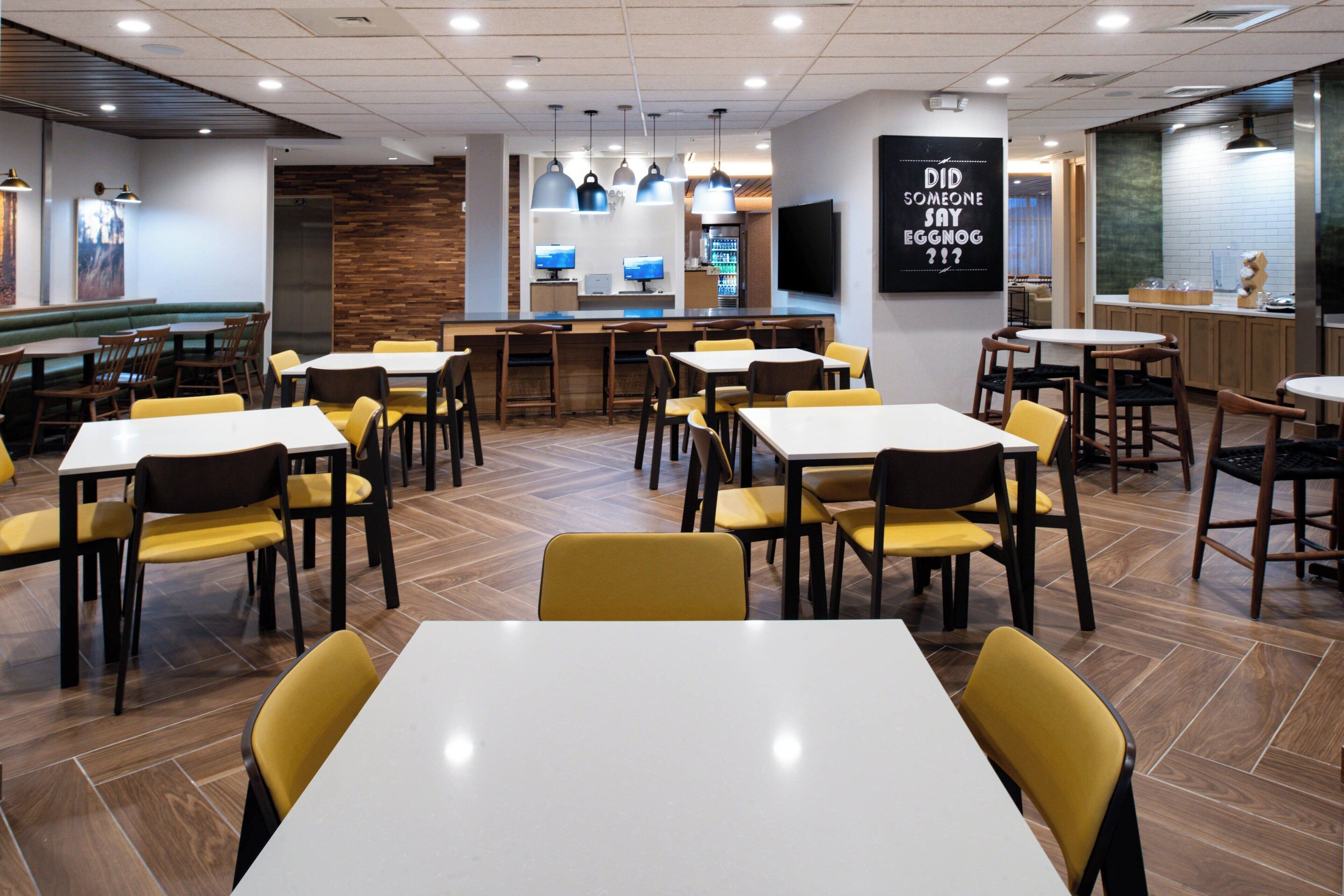 A restaurant with multiple tables and chairs, a bar area, and a kitchen visible in the background.