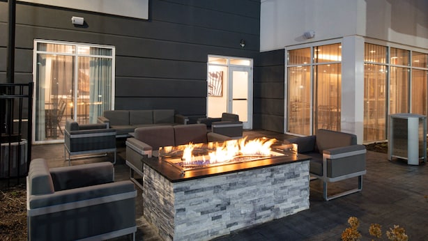 An outdoor seating area with a stone fire feature and modern furniture. - Fairfield Inn & Suites by Marriott Charlotte University Research Park (Charlotte)