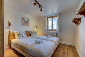 Un dormitorio con dos camas, una ventana, un radiador y un cuadro de una mariposa.