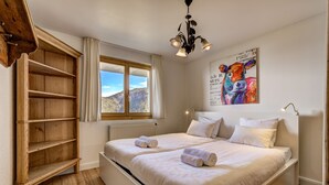 A bedroom with a large bed, wooden shelving unit, and a view of the mountains through a window. - Chalet Claire de Soleil - La Tzoumaz, 4 Vallees (La Tzoumaz)