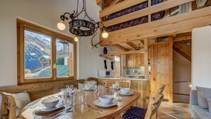A dining area with a wooden table set for four, surrounded by wooden chairs with patterned cushions. - Chalet Claire de Soleil - La Tzoumaz, 4 Vallees (La Tzoumaz)
