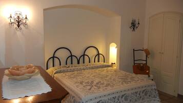 Un dormitorio con cama, mesita de noche, cómoda, lámpara de pared y puerta.