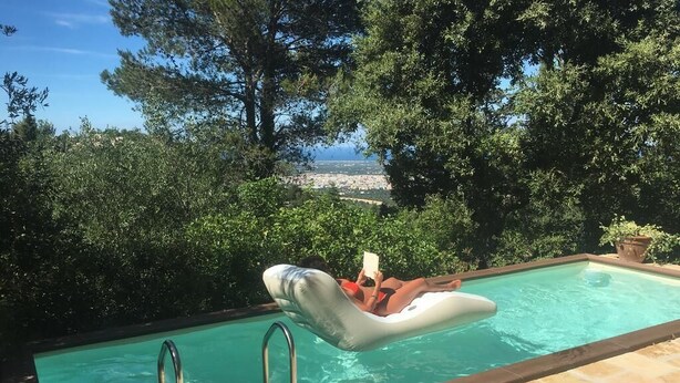 Une piscine offrant une vue sur le paysage urbain, entourée d’arbres.