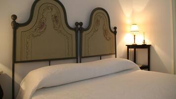 A neatly made bed with a decorative headboard, a bedside table with a lamp, and a wall-mounted light.
