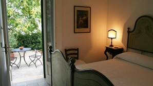 Une chambre à coucher avec un lit, une table de chevet avec une lampe, une chaise et un tableau encadré au mur.