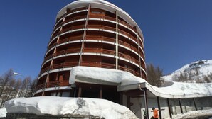 A multi-story building with a curved facade, surrounded by snow-covered ground and trees. - Room Apartment Luxury Duplex view Matterhorn skis - SAUNA - WIFI (Breuil-Cervinia)