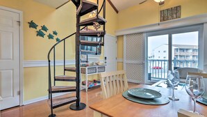 Ein Essbereich mit einem Holztisch, gedeckt für zwei Personen, einer Wendeltreppe und Blick auf den Außenbalkon.