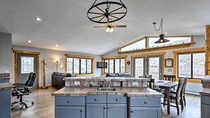 Una cocina amplia con una isla central, vigas de madera, ventanas grandes y un ventilador de techo.