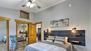 Un dormitorio con cama, mesitas de noche, ventilador de techo y un espejo grande.