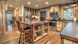 Una cocina moderna con armarios de madera, electrodomésticos de acero inoxidable y una isla central con taburetes de bar.