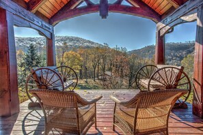 A wooden deck with wicker chairs facing a scenic view of a forested hillside. - The Poplars at Bearwallow Mountain | Two Combined Lodges| Pavilion for Weddings and Events (Hendersonville)