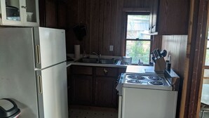 A compact kitchen with wooden cabinets, a white refrigerator, a stove, and a sink. - Rustic Lakefront Cabin near Saugatuck&South Haven (Fennville)