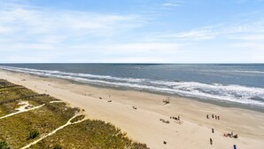 Een strand met een houten vogelzangpad, zandstrand en oceaan.