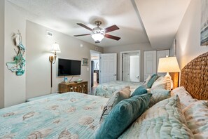 A bedroom with two beds, a ceiling fan, a TV, and a lamp. - Nicely Remodeled & Redecorated Oceanfront Condo + Free Attraction Tickets! (North Myrtle Beach)