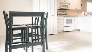 A kitchen with white cabinets, a microwave, an oven, and a dining table with chairs. - Quiet home close to wec (Wilmington)