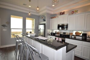 A modern kitchen with white cabinetry, a central island, stainless steel appliances, and pendant lighting.