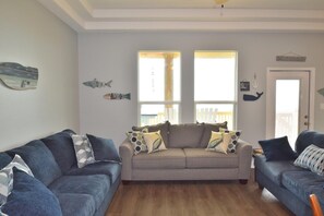 A living room with two sofas, a large window, and decorative fish wall art.