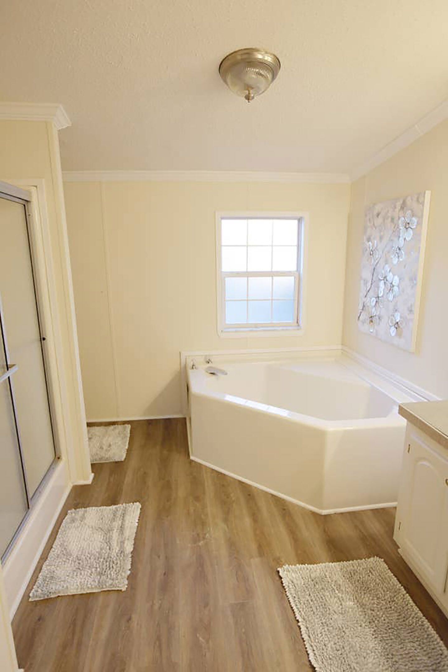 Une salle de bain avec une baignoire, une fenêtre et un tableau au mur.
